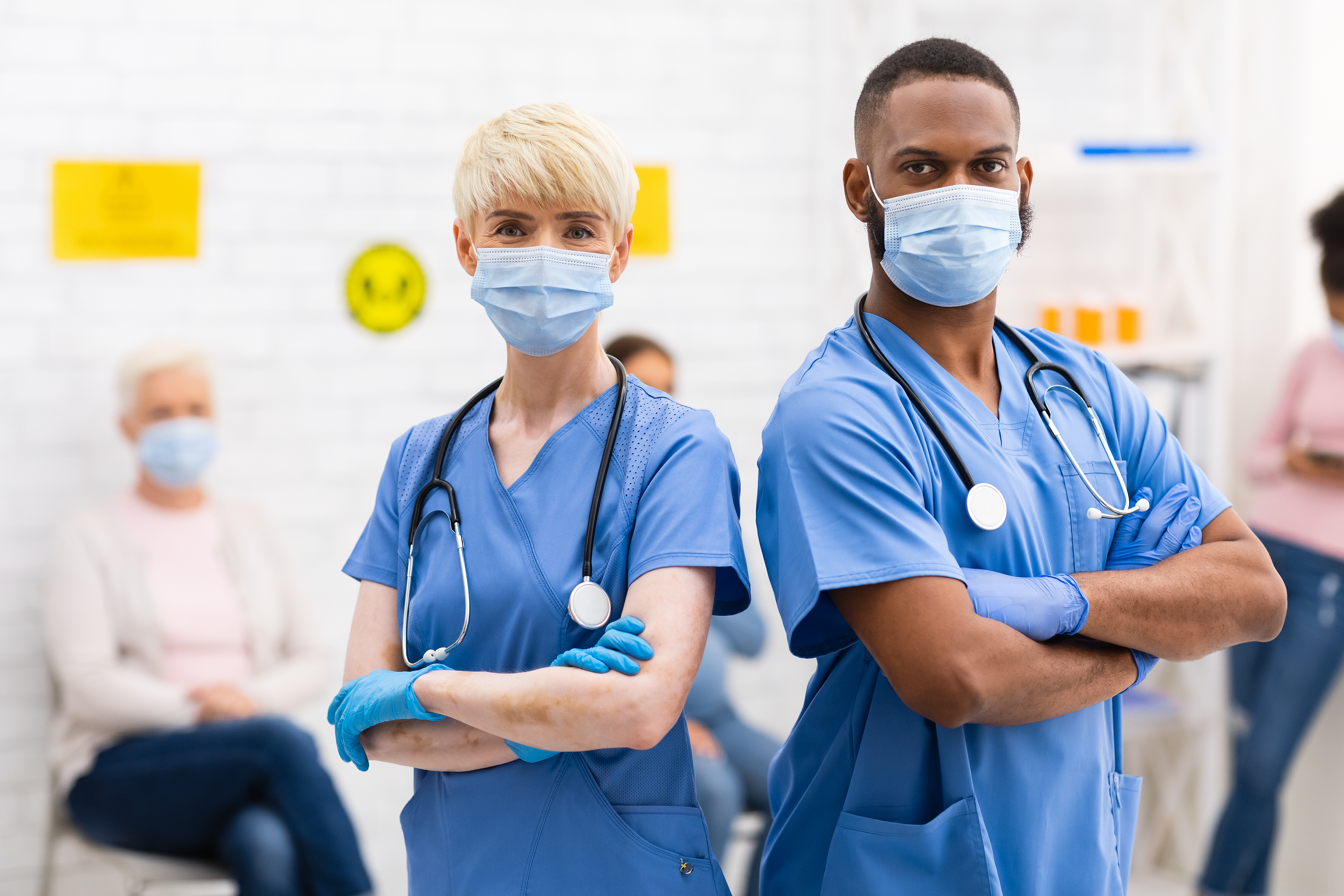 Two nurses wearing masks, arms crossed.