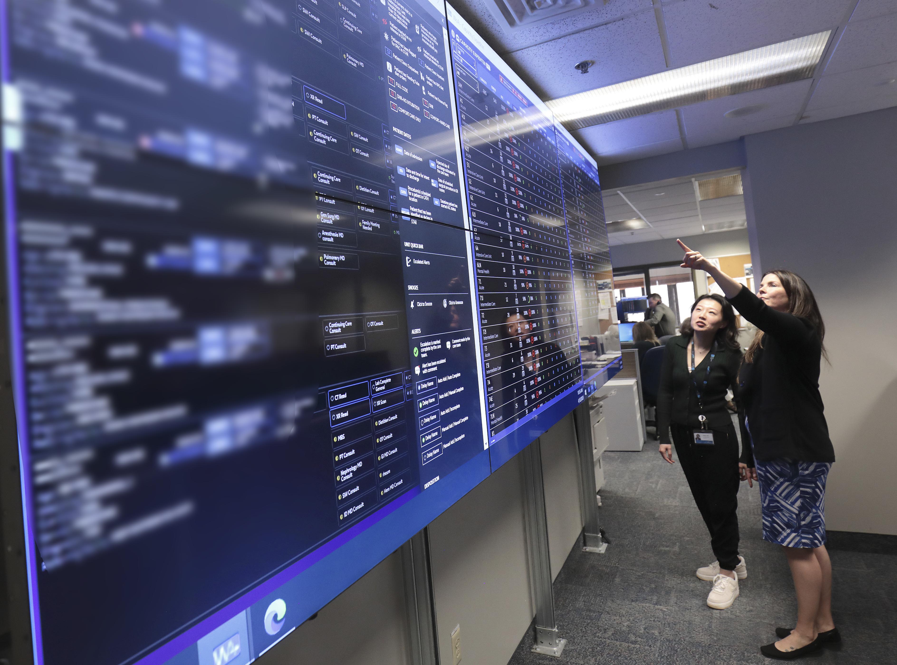 Two women looking at one of the multiple, large computer monitors that make up the Care Coordination Centre.
