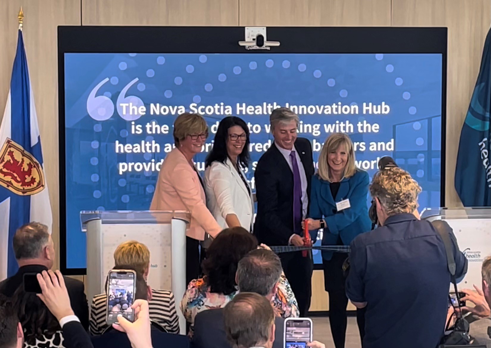 A photo of a ribbon cutting at the opening of the Health Innovation Hub's new office space.