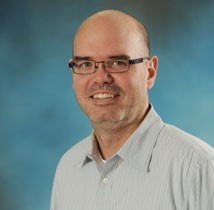 Headshot of Dr. Mark Asbridge against plan blue background