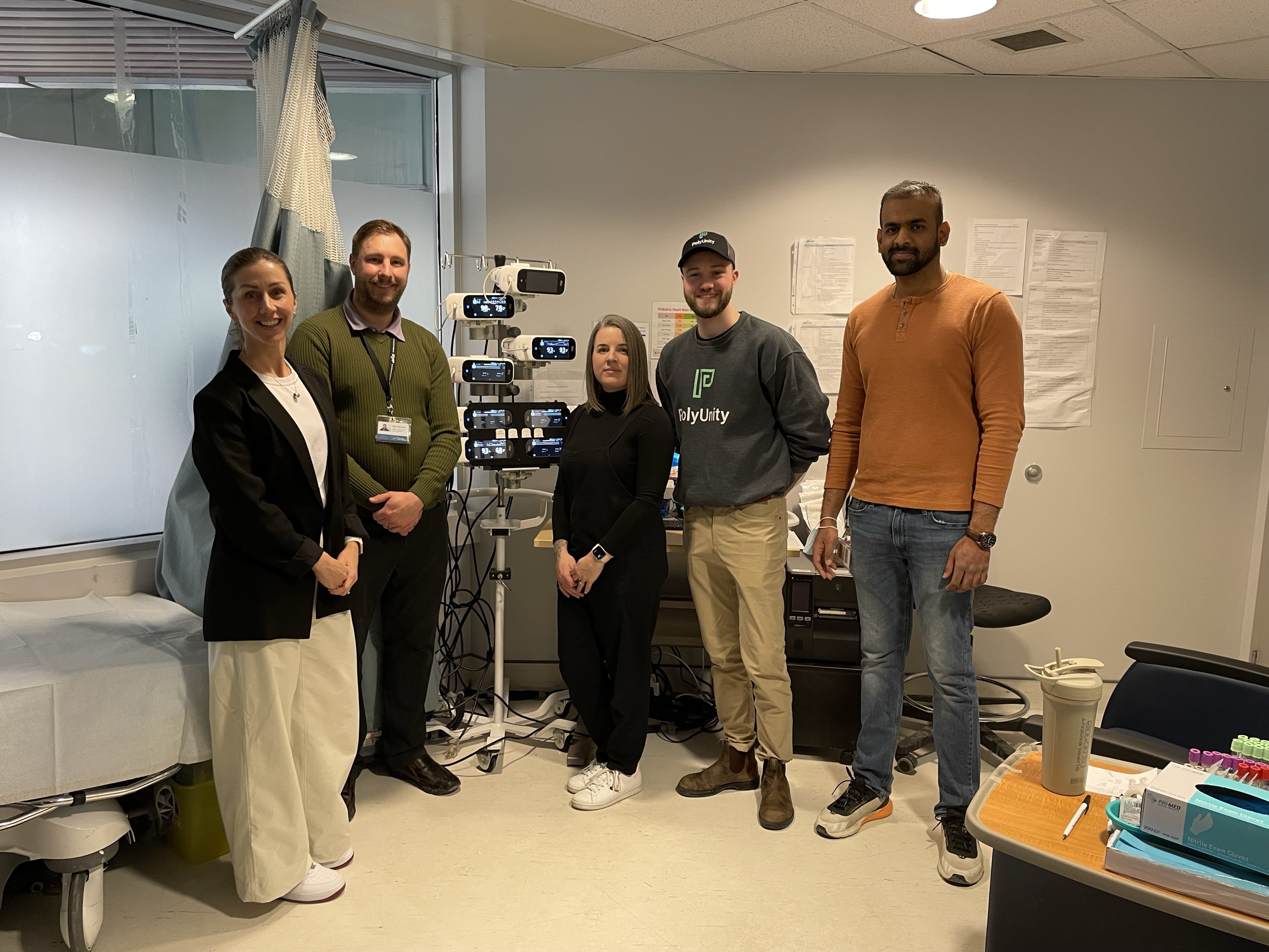 Five people standing around new PolyUnity monitor stand