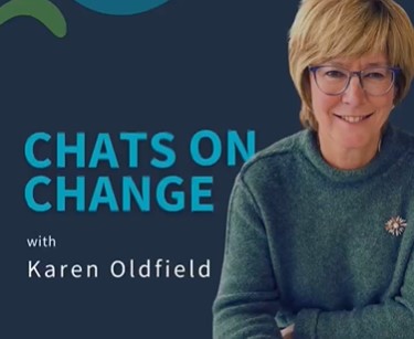 Karen Oldfield smiling at the camera with a cup of coffee