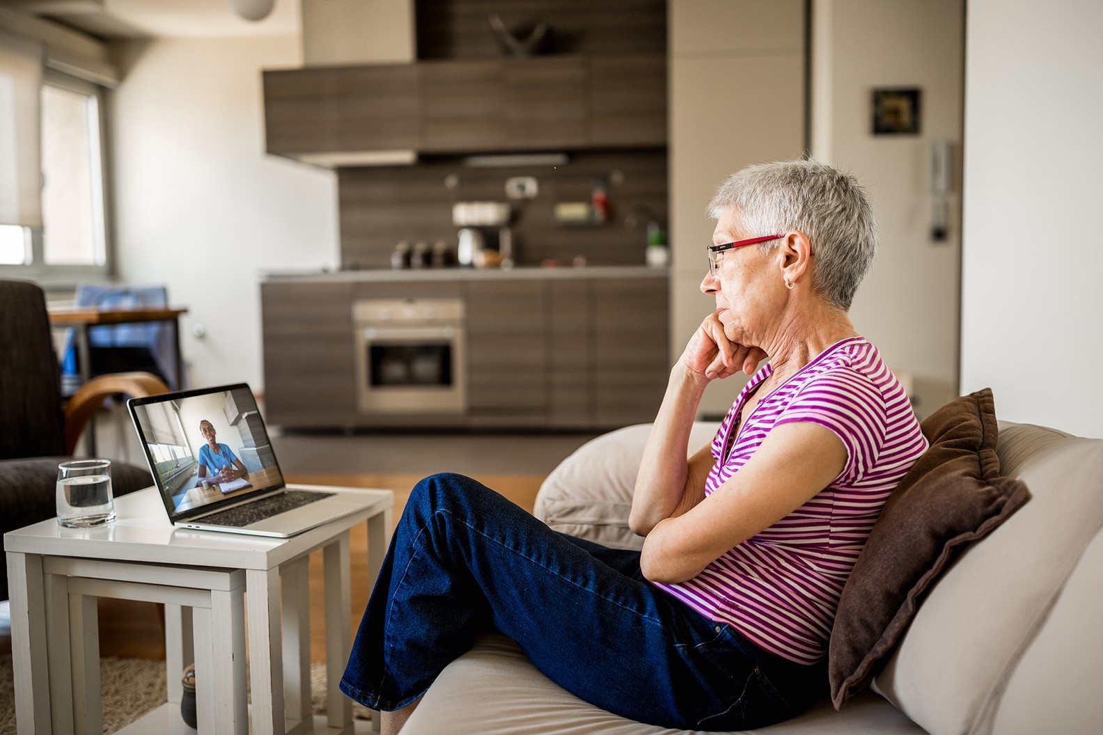Woman meets with support person online from their couch