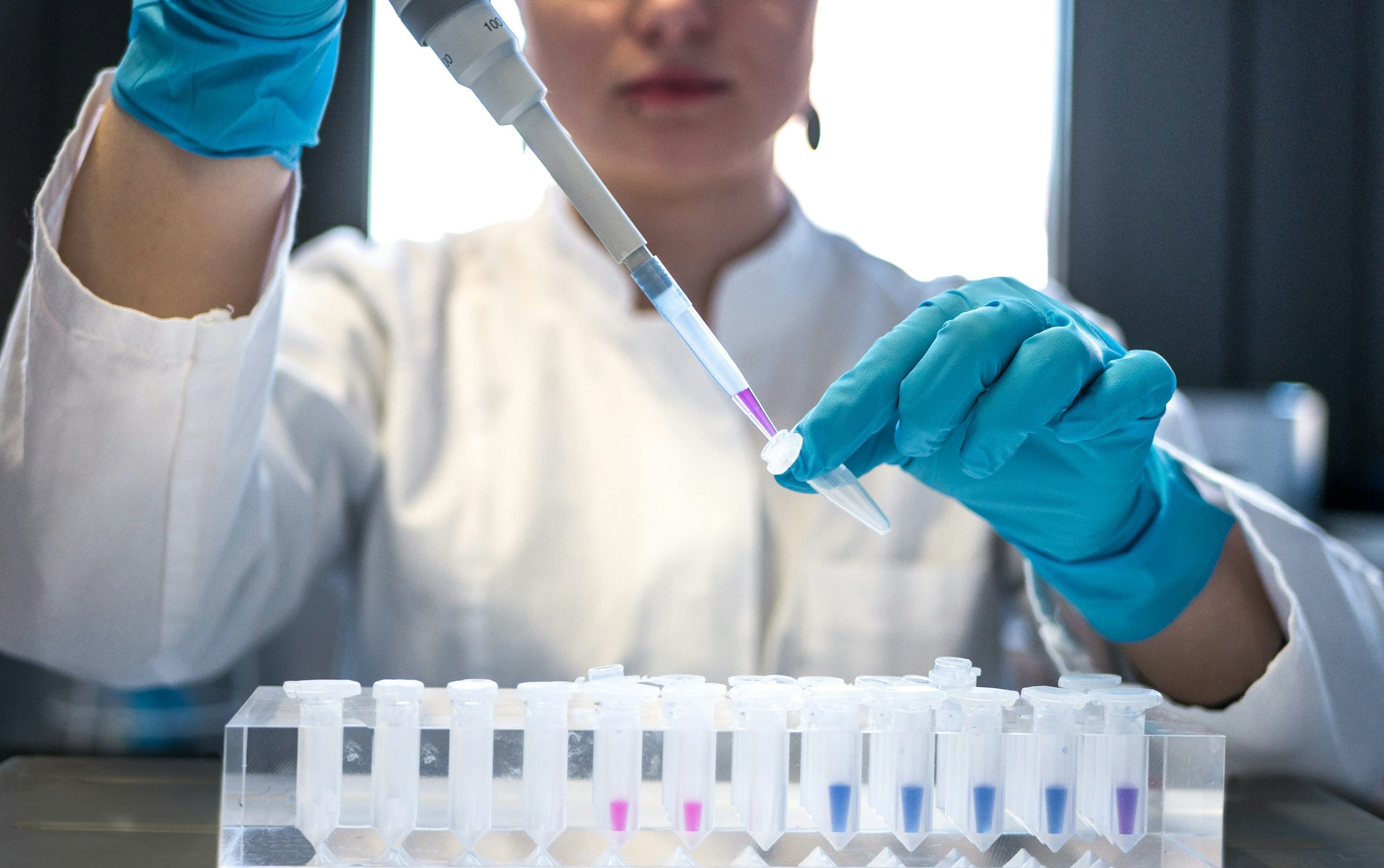 A researcher puts liquid in a vile. 