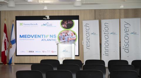 Room with empty chairs and a Medventions slideshow on a big screen