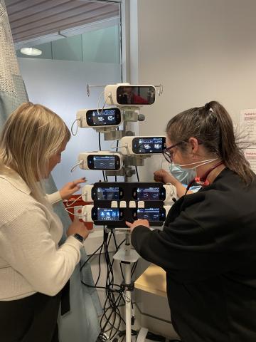 Two healthcare workers looking at a stand with monitors