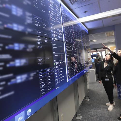 Two women looking at one of the multiple, large computer monitors that make up the Care Coordination Centre.