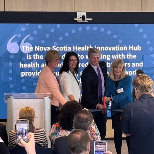 A photo of a ribbon cutting at the opening of the Health Innovation Hub's new office space.