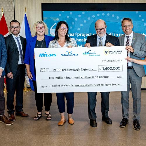 A group of people holding a large cheque at the Mitacs announcement