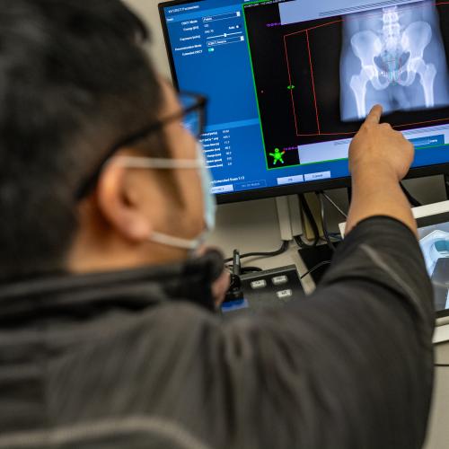A technician pointing at an MRI scan on a computer screen