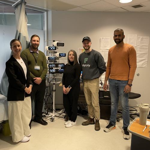 Five people standing around new PolyUnity monitor stand