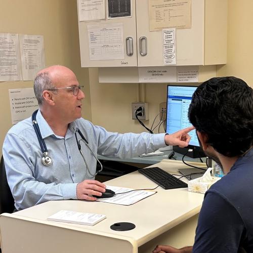 Dr. Ransom in an office showing a screen to a patient. 